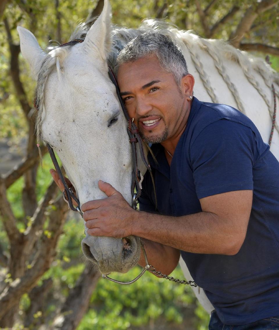 In this Oct. 18, 2012 photo, Cesar Millan poses with his horse Conquistador at his Dog Psychology Center, in Santa Clarita, Calif. Millan has a new television show, book, tour and documentary. "Cesar Millan: The Real Story" airs on Nat Geo Wild on Nov. 25, 2012. It will also launch a global speaking tour. (AP Photo/Mark J. Terrill)