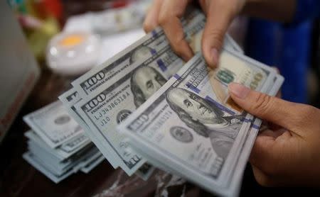 An employee of a bank counts US dollar notes at a branch in Hanoi, Vietnam May 16, 2016. REUTERS/Kham