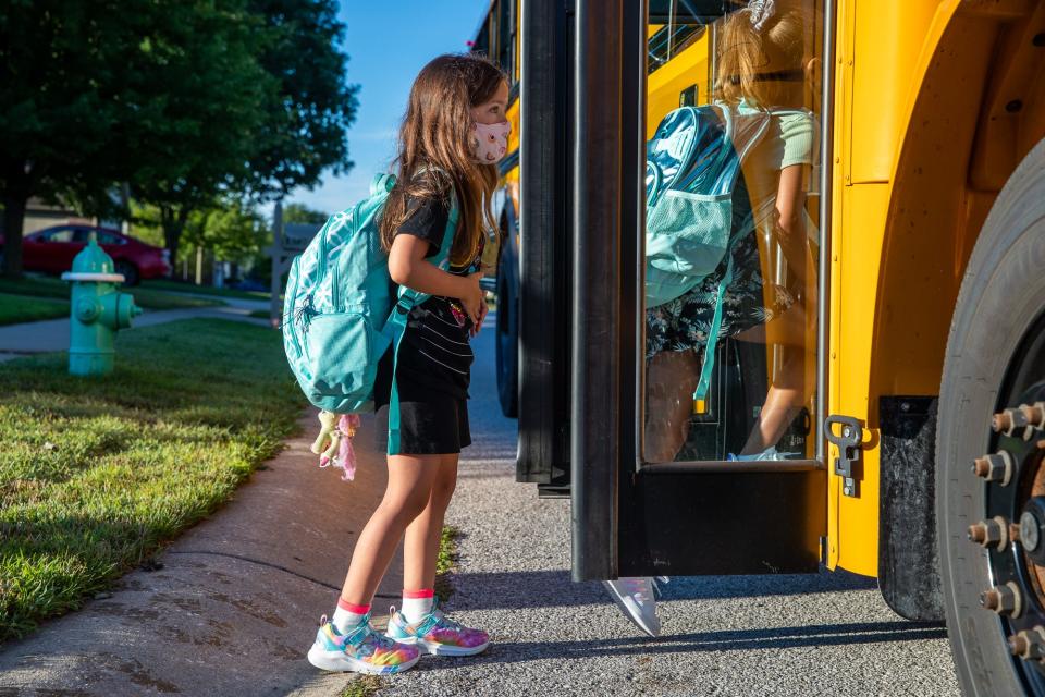 Third grader Hadley Steckler enters a school bus with other students on the way to Sycamore Elementary School in Avon, Ind.