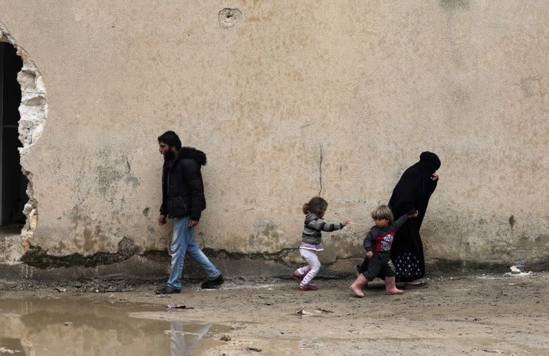 Internally displaced people walk at an empty school and university compound used as shelter, in Azaz