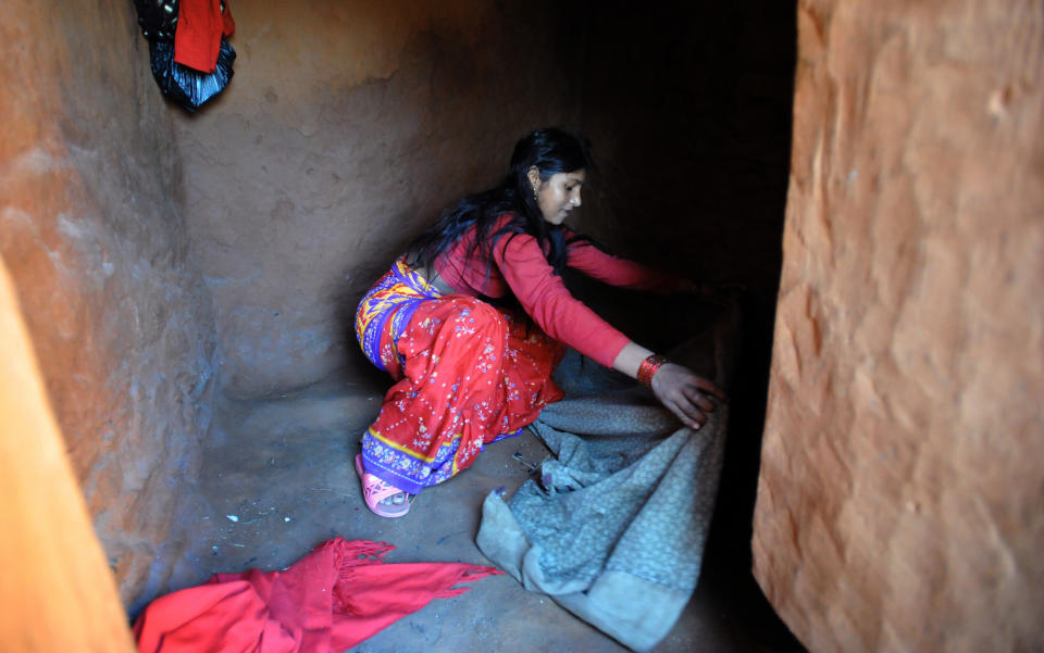 Nepalese villager Chandrakal Nepali prepares her bedding inside a 'chhaupadi house.' Isolation is part of a centuries-old Hindu ritual blamed for prolongued depression, young women's deaths and high infant mortality rates in remote, impoverished western Nepal. Under the practice women are prohibited from participating in normal family activities during menstruation and after childbirth.