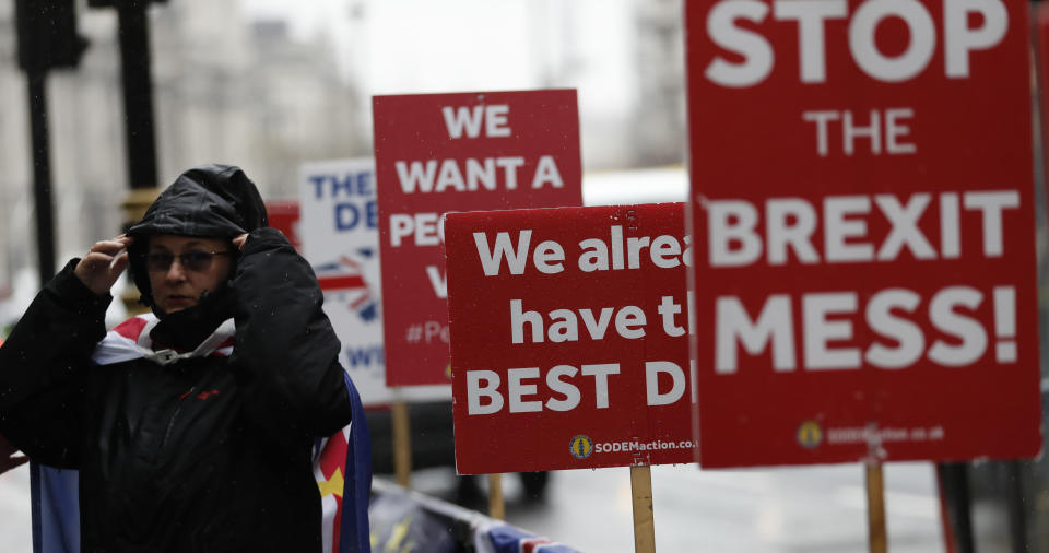 An anti Brexit protester with placards, stand in the rain as they demonstrate outside the Houses of Parliament in London, Tuesday, April 2, 2019. Britain's Prime Minister Theresa May is set for long Cabinet meeting Tuesday, as the government tries to find a way out of the Brexit crisis, after lawmakers on Monday rejected all alternatives to her European Union withdrawal agreement. (AP Photo/Alastair Grant)