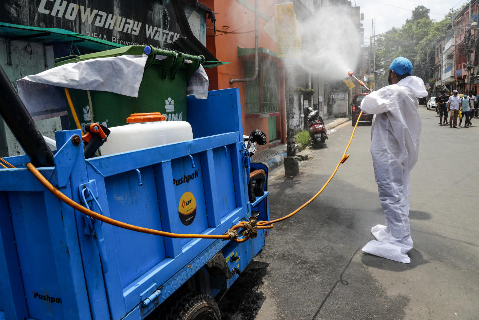 A civic worker sprays sanitizers in front of roadside shops in Kolkata, India, Sunday, Aug. 30, 2020. India has the third-highest coronavirus caseload after the United States and Brazil, and the fourth-highest death toll in the world. (AP Photo/Bikas Das)