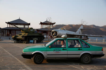 A taxi is parked in front of retired airplane and tank on display, at a Chinese village bordering North Korea at Dandong in China's Liaoning Province, April 13, 2017. REUTERS/Aly Song