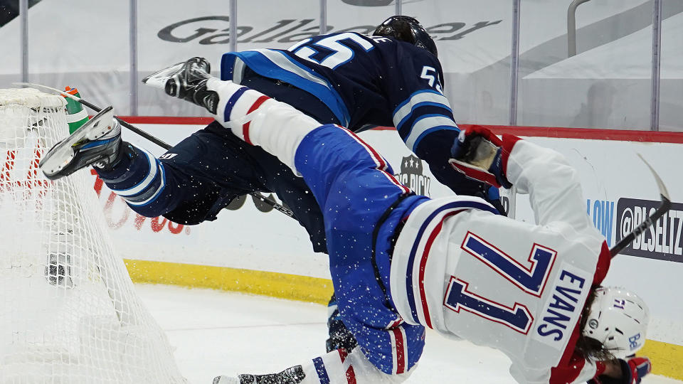 WINNIPEG, MB - JUNE 2: Jake Evans #71 of the Montreal Canadiens is left injured after scoring a third period empty net goal and then checked hard by Mark Scheifele #55 of the Winnipeg Jets in Game One of the Second Round of the 2021 Stanley Cup Playoffs on June 2, 2021 at Bell MTS Place in Winnipeg, Manitoba, Canada. (Photo by David Lipnowski/Getty Images)