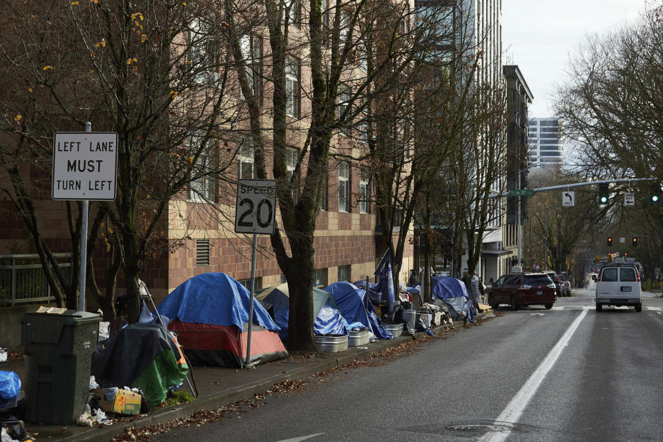 FILE - Tents line the sidewalk on SW Clay St in Portland, Ore., on Dec. 9, 2020. Portland Mayor Ted Wheeler announced this morning Friday, Oct. 21, 2022, that the city will ban homeless street camping in the coming months as it creates new, large "designated" camping sites in a bid to address the city's homelessness crisis. Oregon's reputation for political harmony is being tested as a Republican walkout in the state Senate continues for a third week. The boycott could derail hundreds of bills and approval of a biennial state budget, as Republicans and Democrats refuse to budge on their conflicting positions over issues including abortion rights, transgender health and guns. (AP Photo/Craig Mitchelldyer, File)