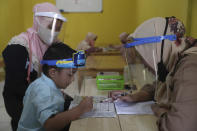 Teachers and students wear protective gear as a precaution against the new coronavirus outbreak during a class at a Quran educational facility at on the outskirts of Jakarta, Indonesia, Wednesday, July 1, 2020. The government of Indonesia's capital region is extending the first transition phase from large-scale social restrictions in Jakarta as the number of new confirmed coronavirus cases continues to rise. (AP Photo/Tatan Syuflana)