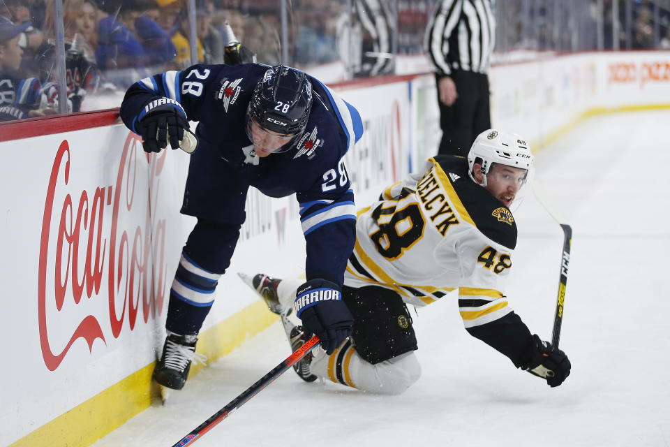 Winnipeg Jets' Jack Roslovic (28) gets checked by Boston Bruins' Matt Grzelcyk (48) during the second period of an NHL hockey game Friday, Jan. 31, 2020, in Winnipeg, Manitoba. (John Woods/The Canadian Press via AP)