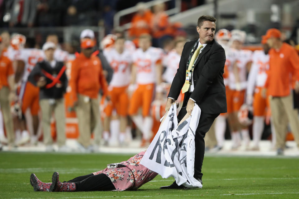 A woman appeared to be staging a protest at Monday’s title game and was dragged off the field by police. (Getty)