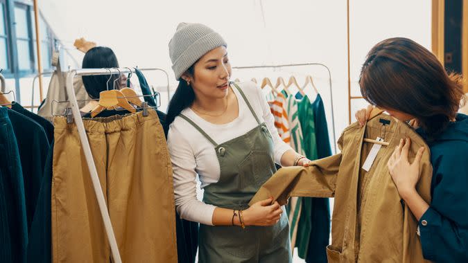 Retail shop clerk helping a mid adult woman customer shop for clothing in a boutique in Japan.