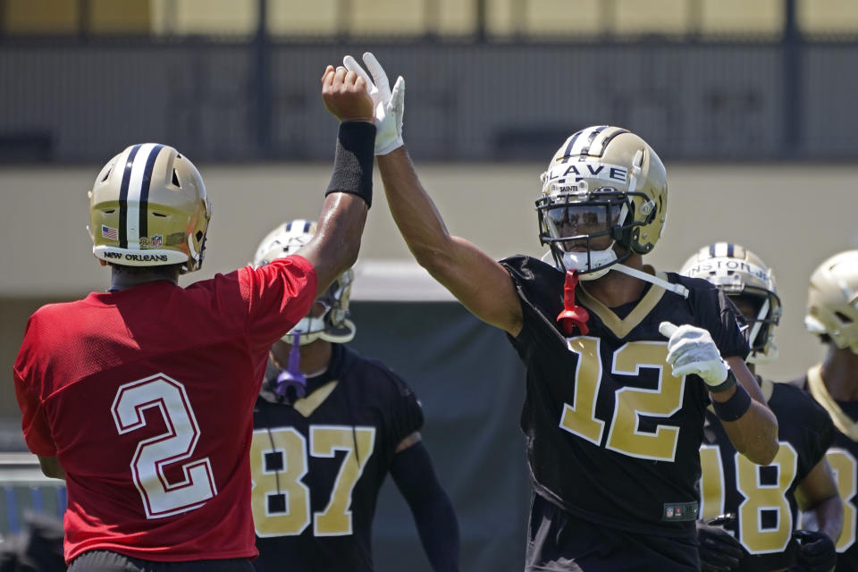 FILE - New Orleans Saints first round draft pick, wide receiver Chris Olave (12), high fives quarterback Jameis Winston (2) during an NFL football practice in Metairie, La., Thursday, June 2, 2022. (AP Photo/Gerald Herbert, File)