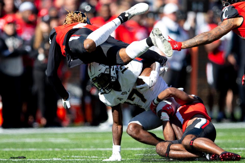 Cincinnati Bearcats safety Bryan Cook (6) and Cincinnati Bearcats cornerback Coby Bryant (7) tackle UCF Knights wide receiver Amari Johnson (17) in the second half of the NCAA football game on Saturday, Oct. 15, 2021, at Nippert Stadium in Cincinnati. Cincinnati Bearcats defeated UCF Knights 56-21.