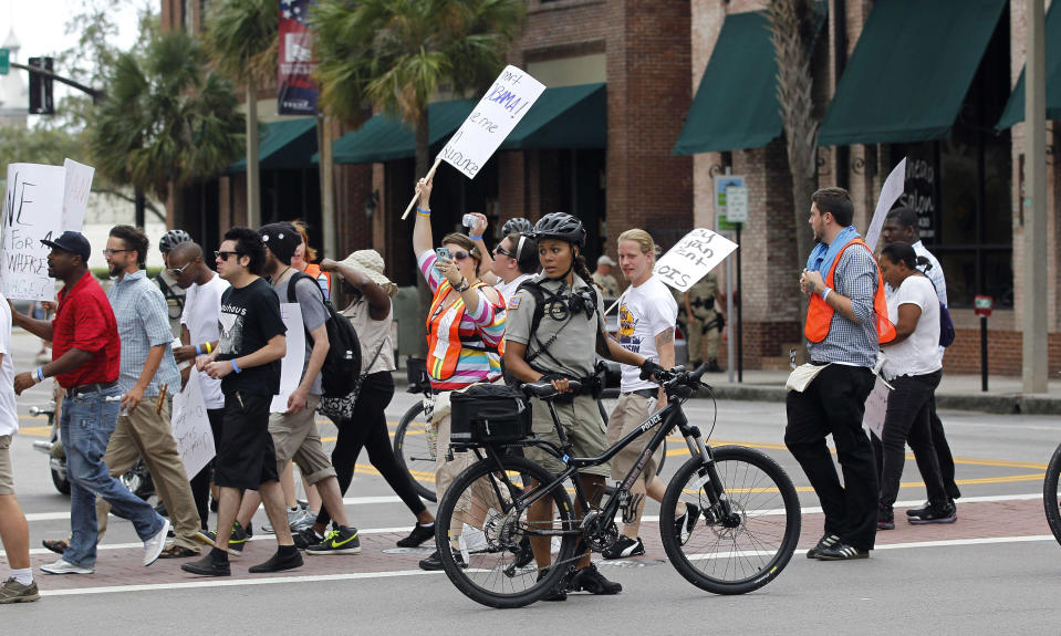 Tampa, Fla., police officers on bicycles watch demonstrators as they cross the street to attend a rally Sunday, Aug. 26, 2012, in Tampa, Fla. Hundreds of protestors gathered in Gas Light Park in downtown Tampa to march in demonstration against the Republican National Convention. (AP Photo/Dave Martin)