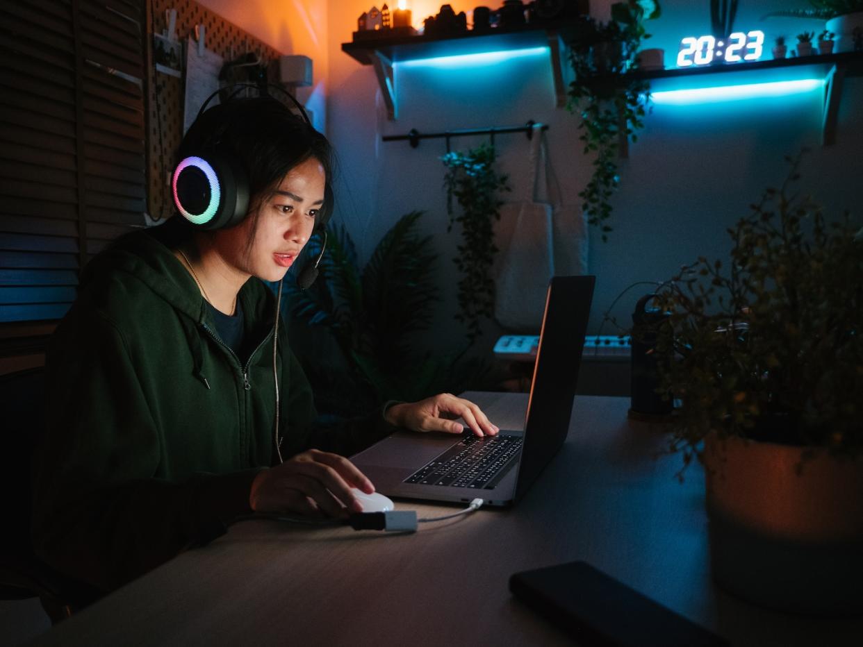 Female youth with headset playing online video game in room (Photo: Getty Images)