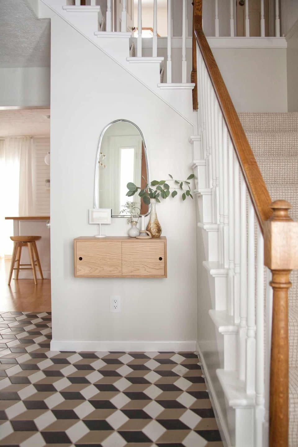 a white hallway with a mirror and a floating wood shelf