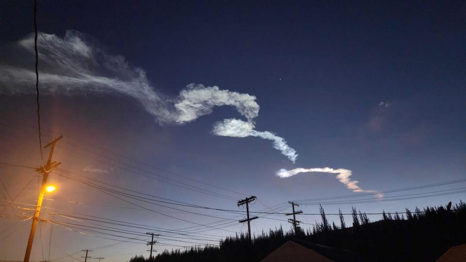 The rocket contrail snakes through the sky above Highland Park.