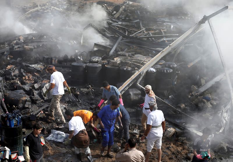 FILE PHOTO: Workers salvage oil canisters from the wreckage of a vehicle oil and tires store hit by Saudi-led air strikes in Sanaa