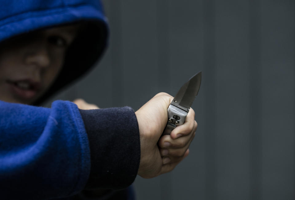 Boy holding knife ready to attack someone