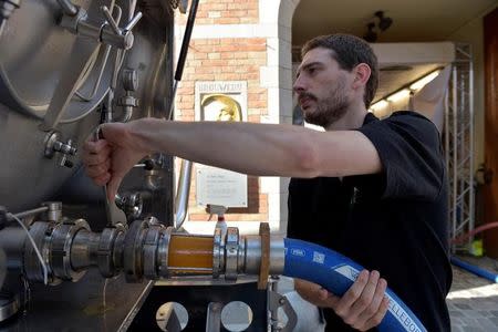 An employee of De Halve Maan brewery connects a pipe to feed beer into a truck in Bruges, September 15, 2016. REUTERS/Eric Vidal