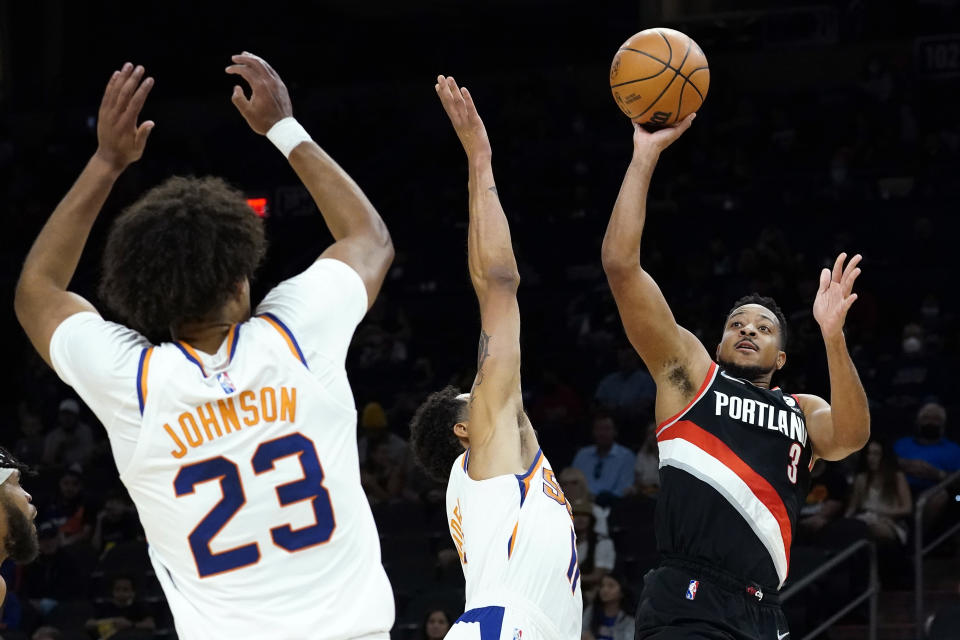 Portland Trail Blazers guard CJ McCollum (3) shoots over Phoenix Suns forward Abdel Nader and forward Cameron Johnson (23) during the first half of a preseason NBA basketball game, Wednesday, Oct. 13, 2021, in Phoenix. (AP Photo/Matt York)