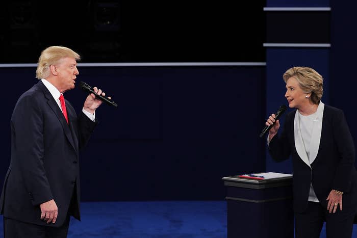 Donald and Hillary holding microphones onstage and looking at each other