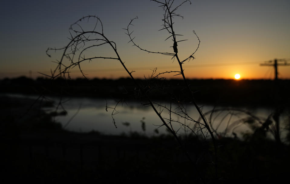 The sun sets over the Rio Grande in Eagle Pass , Texas, Thursday, July 6, 2023, where concertina wire lines the banks of the river that has been recently bulldozed. Texas Republican Gov. Greg Abbott has escalated measures to keep migrants from entering the U.S. He's pushing legal boundaries along the border with Mexico to install razor wire, deploy massive buoys on the Rio Grande and bulldozing border islands in the river. (AP Photo/Eric Gay)