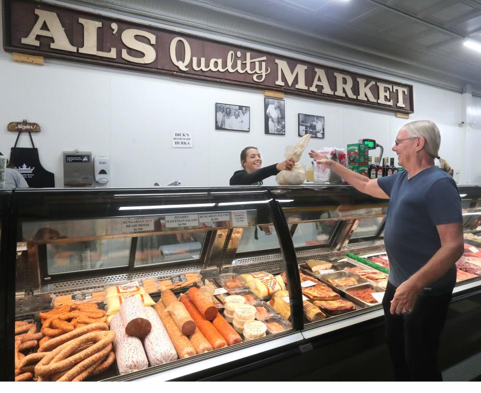 Al's Quality Market employee Stacey Querry hands a customer his meat purchase on Wednesday, August 16, 2023 in Barberton, Ohio. The Market has been a fixture in Barberton for 75 years.