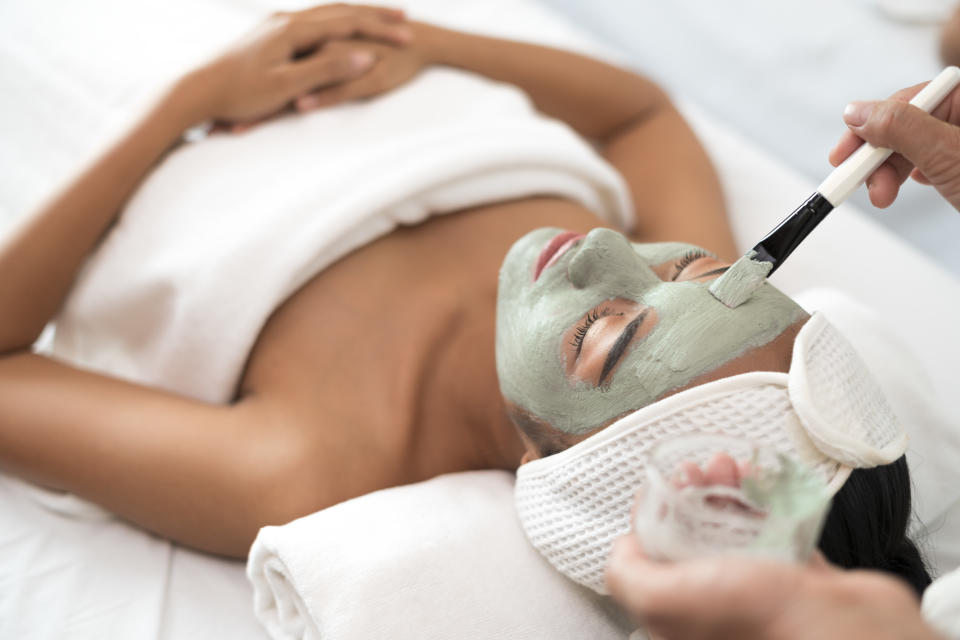 Closeup of a beauty therapist applying a face mask to woman client