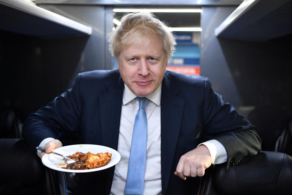 Britain's Prime Minister Boris Johnson eats a portion of pie on the campaign bus after a visit to the Red Olive catering company in Derby, Britain December 11, 2019 on the final day of campaigning before a general election. Ben Stansall/Pool via REUTERS