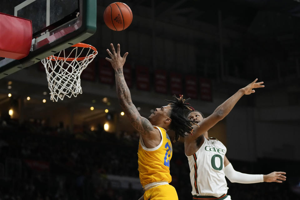 Pittsburgh guard Nike Sibande (22) shoots past Miami forward A.J. Casey (0) during the first half of an NCAA college basketball game, Saturday, March 4, 2023, in Coral Gables, Fla. (AP Photo/Rebecca Blackwell)