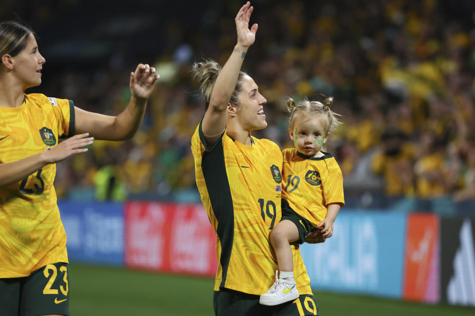 Australia's Kyra Cooney-Cross, left, and Australia's Katrina Gorry with her daughter Harper celebrate after winning the Women's World Cup quarterfinal soccer match between Australia and France in Brisbane, Australia, Saturday, Aug. 12, 2023. (AP Photo/Tertius Pickard)