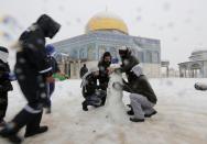 People build a snowman in front of the Dome of the Rock in the compound known to Muslims as Noble Sanctuary and to Jews as Temple Mount, in Jerusalem's Old City December 12, 2013. Snow fell in Jerusalem and parts of the occupied West Bank where schools and offices were widely closed and public transport was paused. REUTERS/Ammar Awad (JERUSALEM - Tags: RELIGION ENVIRONMENT)