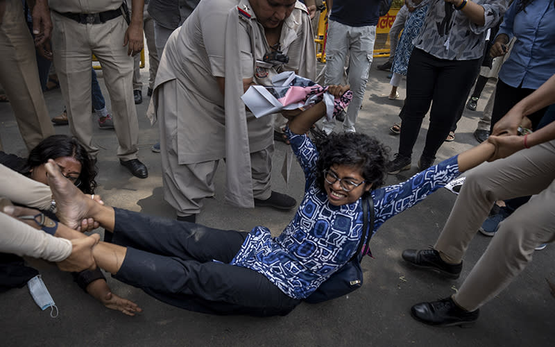 Police carry a protester by their hands and feet