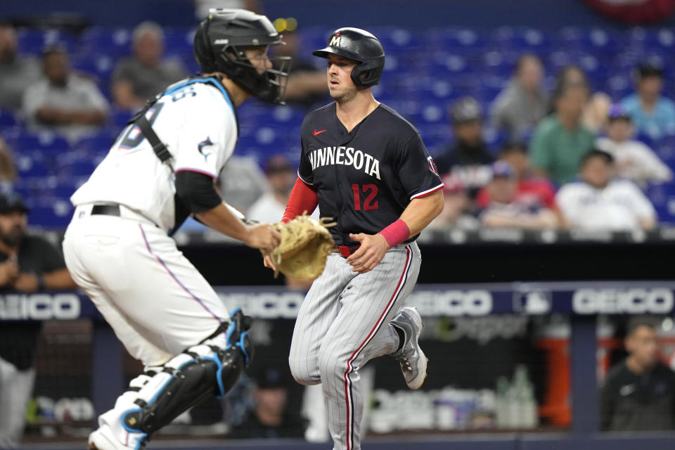 Minnesota Twins' Kyle Farmer (12) runs past Miami Marlins catcher Jacob Stallings to score on a double hit by Carlos Correa during the fourth inning of a baseball game, Monday, April 3, 2023, in Miami. (AP Photo/Lynne Sladky)