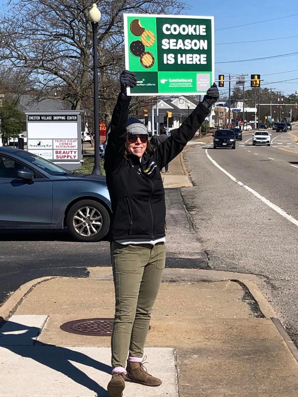 Dina Phelps draws attention to her daughter Marian's Girl Scout drive-thru cookie booth in the Chester Village Shopping Center on Saturday, February 18 in Chester.