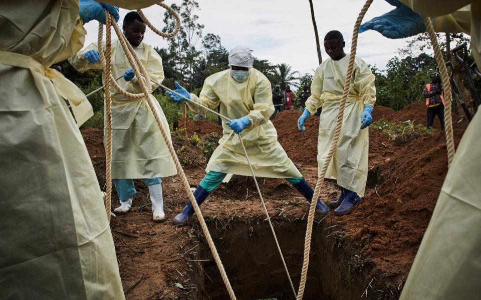 Health workers lower the coffin of an Ebola victim in the DRC - the outbreak has killed more than 2,000 people since August 2018 - REX