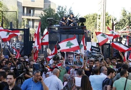 Activists carry banners, Lebanese flags and pictures of Syria's President Bashar al-Assad as policeman secure the area during a sit-in near the U.S. embassy in Awkar, north of Beirut, against potential U.S. strikes on Syria September 6, 2013. U.S. officials ordered non-emergency personnel and their family members out of Lebanon on Friday "due to threats," the U.S. embassy in Beirut said in statement. REUTERS/Mohamed Azakir