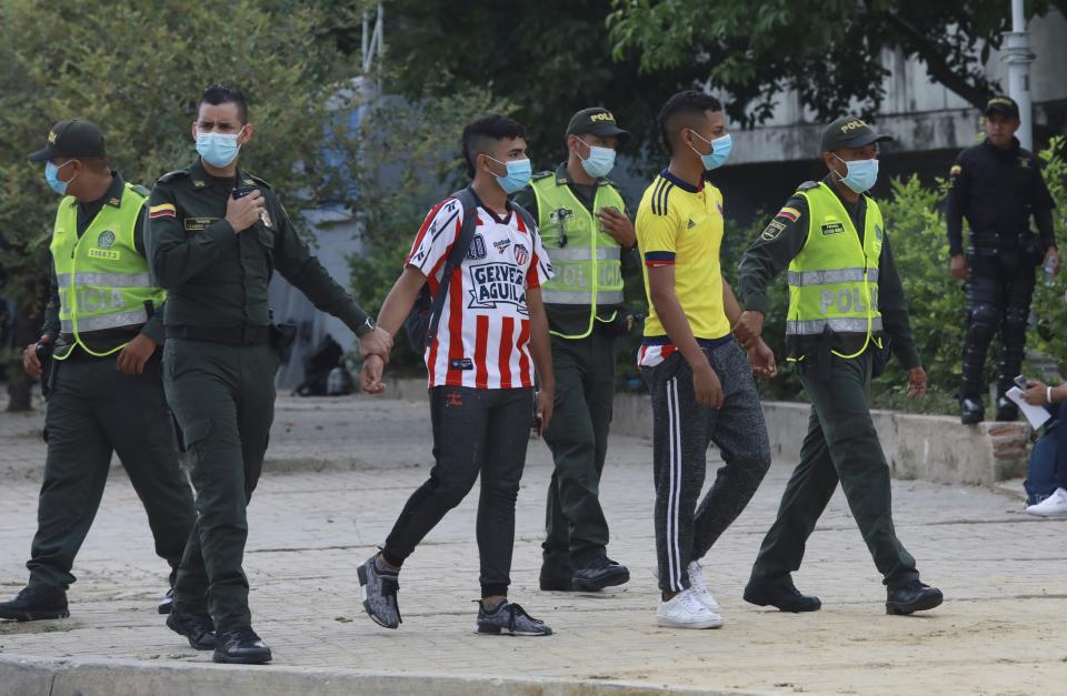 Police detain two men during a protest near the stadium that will host the FIFA World Cup Qatar 2022 qualifying soccer match between Argentina and Colombia, in Barranquilla, Colombia, Tuesday, June 8, 2021. The protest is coined "A red card for indifference" referring to an ongoing wave of protests triggered by a proposed plan to increase taxes. (AP Photo/Jairo Cassiani)