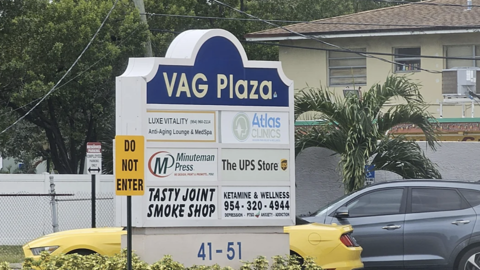 Sign with "VAG Plaza" and multiple businesses listed: Luxe Vitality Anti-Aging Lounge & MedSpa, Atlas Clinics, Minuteman Press, The UPS Store, Tasty Joint Smoke Shop, Ketamine & Wellness