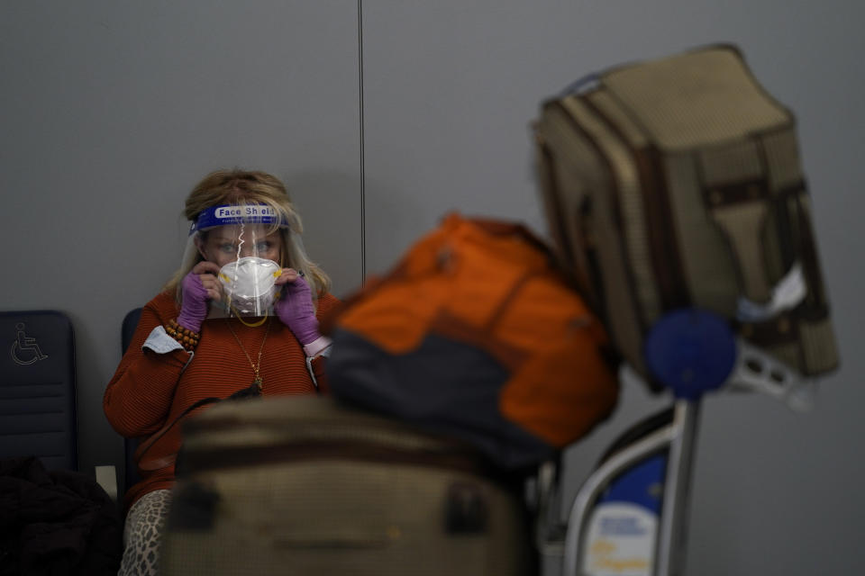 FILE - In this Nov. 23, 2020, file photo a traveler adjusts her mask while waiting to check in for her flight at the Los Angeles International Airport in Los Angeles. A survey from the Associated Press-NORC Center for Public Affairs Research finds about 4 in 10 Americans say they are extremely or very worried about themselves or a family member being infected with the virus, about the same as in October and slightly lower than in surveys conducted in March and in July (AP Photo/Jae C. Hong, File)
