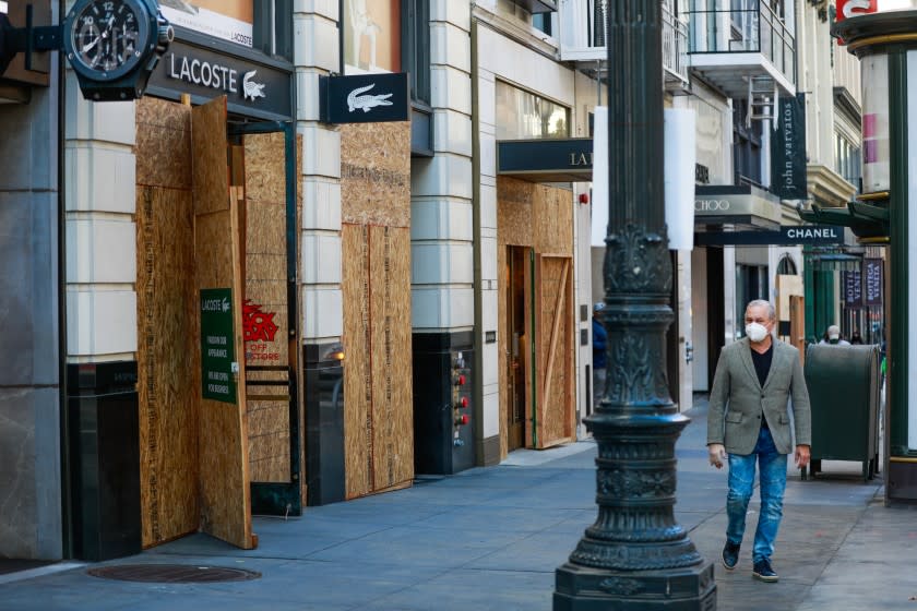 A man passes by boarded up storefronts in San Francisco.