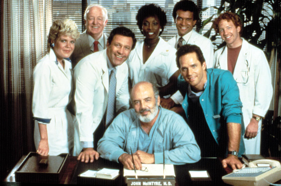 The ‘Trapper John, M.D.’ cast in 1985, from left: Christopher Norris, Simon Scott, Charles Siebert, Madge Sinclair, Pernell Roberts (seated), Brian Mitchell, Gregory Harrison and Timothy Busfield - Credit: Everett Collection