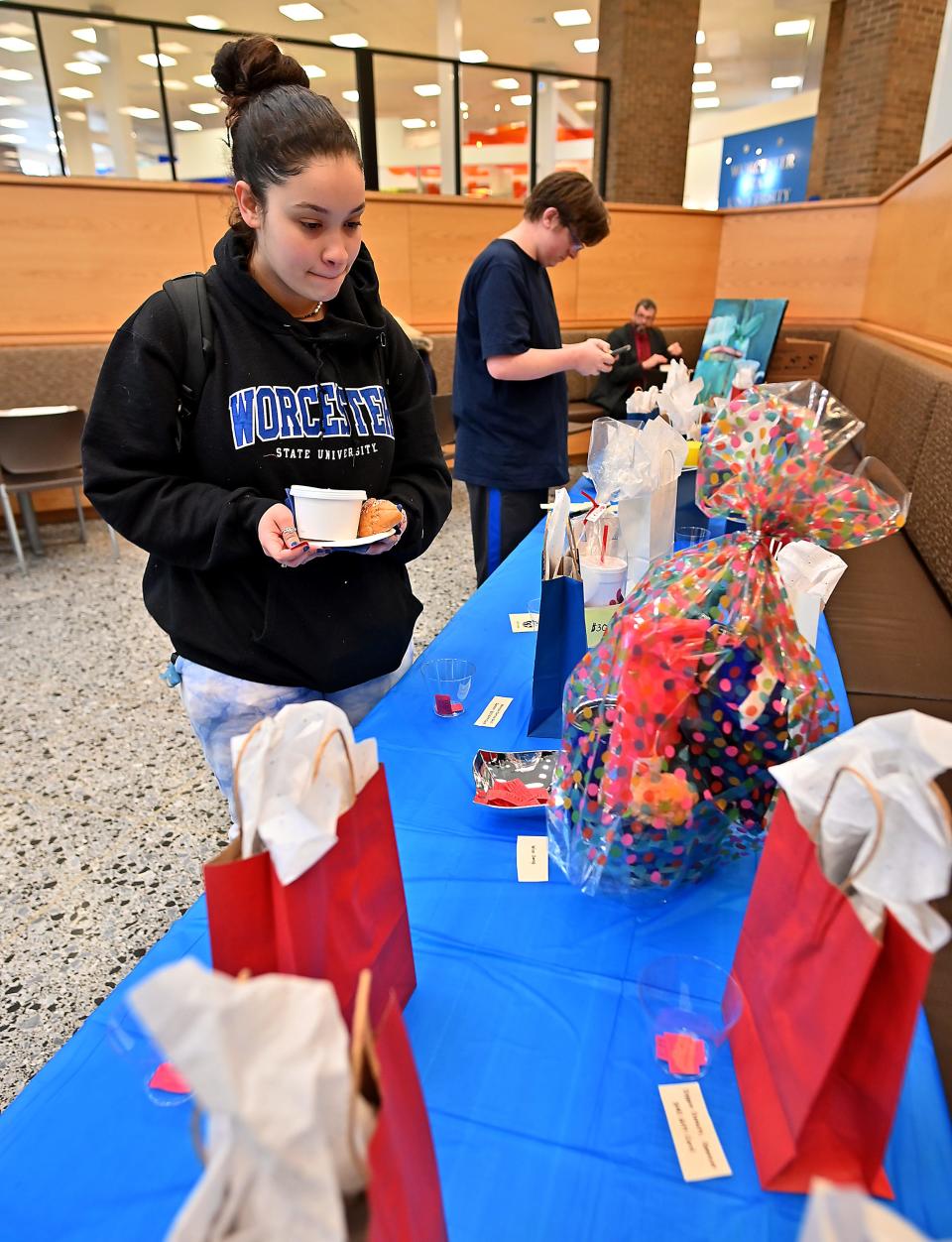 Worcester State University junior Karoline Santo of Marlborough decides which prizes to bid for with her raffle tickets during a campus fundraiser to collect money for the university's food pantry, Thea's Pantry.