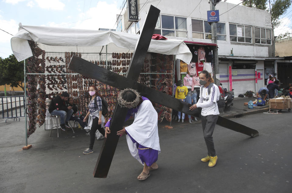 Un cristiano carga una cruz mientras representa la crucificción de Cristo en Iztapalapa, en las afueras de la Ciudad de México, el viernes 2 de abril de 2021, en medio de la nueva pandemia de coronavirus. Para ayudar a prevenir la propagación del COVID-19, la recreación más famosa de América Latina de la crucifixión de Cristo se cerró al público y se transmitió en vivo para que la gente pudiera verla en casa, por segundo año consecutivo. (AP Foto/Marco Ugarte)