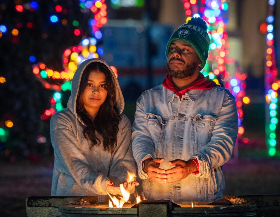 Gabby Perdomo and her father, Eddy Perdomo, of Worcester warm their hands by a fire during the city’s annual Festival of Lights on Friday.