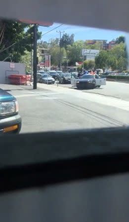 Police officers take position after a suspected gunman being pursued by police crashed his car and then went into a Trader Joe's store in Los Angeles, California, the U.S., July 21, 2018, in this still image taken from a video obtained from social media. @Lorisqueen/via REUTERS