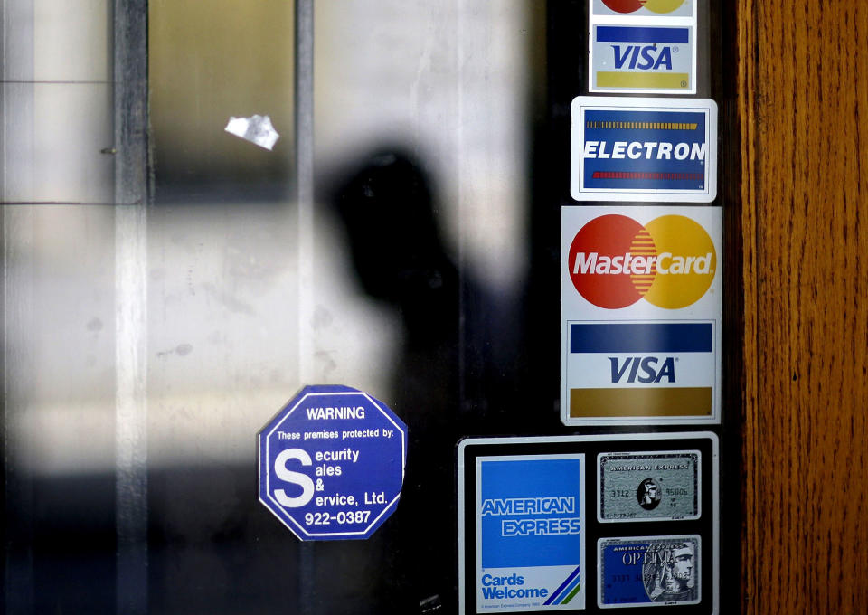 A pedestrian walks past credit card signs posted on a storefront in downtown Atlanta.  (Credit: David Goldman, AP Photo)