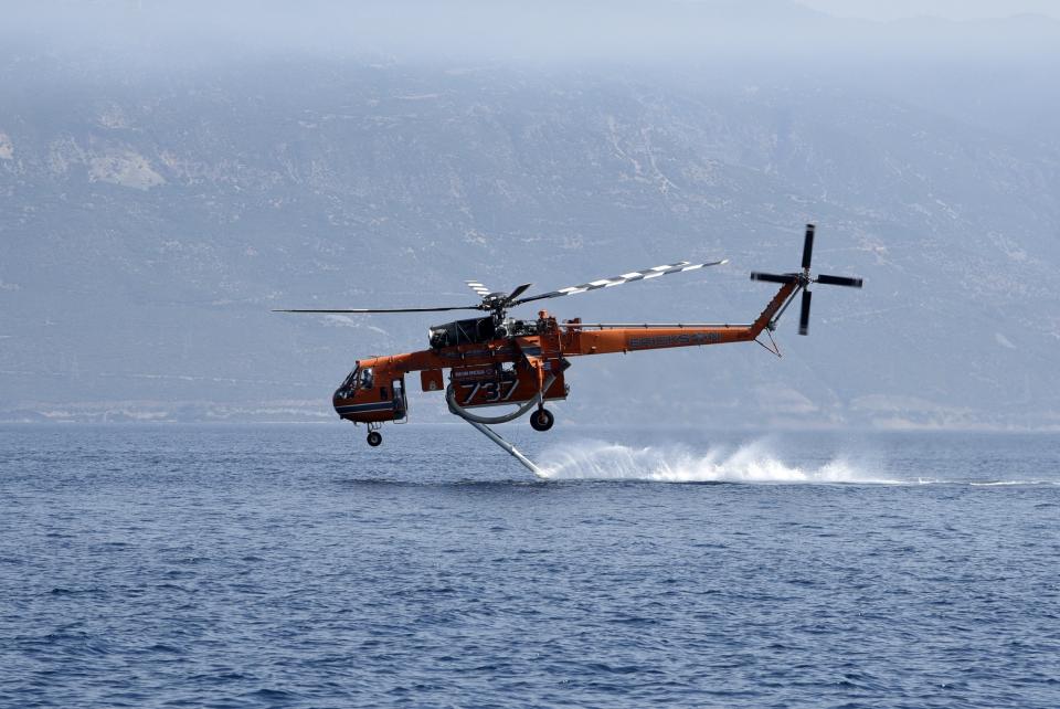 A helicopter fills up with water from the sea near Lampiri village, east of Patras city, Greece, Sunday, Aug. 1, 2021. A wildfire that broke out Saturday in western Greece forced the evacuation of four villages and people on a beach by the Fire Service, the Coast Guard and private boats, authorities said. (AP Photo/Andreas Alexopoulos)