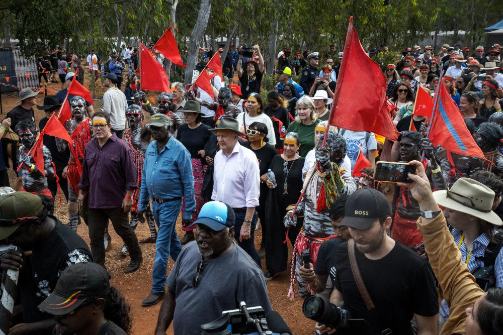Luke Gosling, Djawa Yunupingu and Anthony Albanese, are escorted through the Garma camp site by the Red Flag Dancers