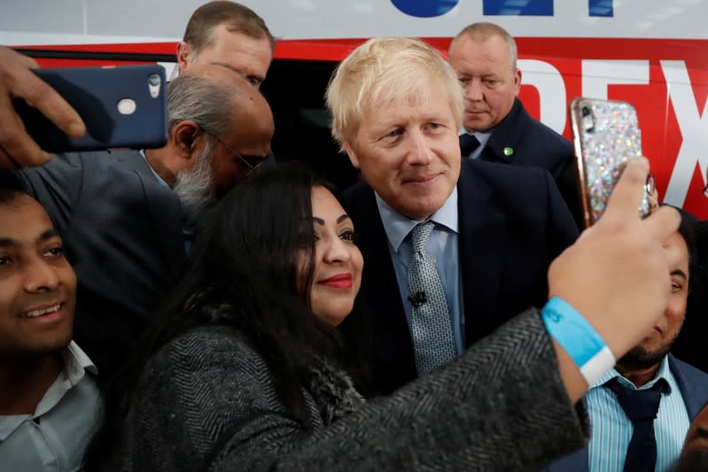 Britain's Prime Minister Boris Johnson poses for a picture with a supporter in front of the general election campaign trail bus in Manchester